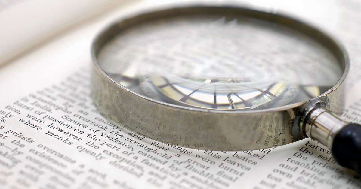 magnifying glass sitting on top of open page with indiscernible text